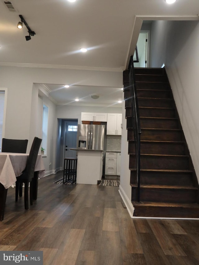 stairs with hardwood / wood-style flooring, ornamental molding, and track lighting