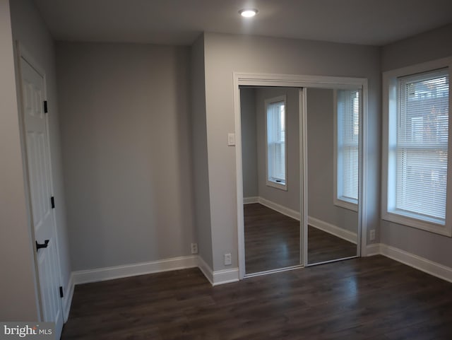 unfurnished bedroom featuring dark hardwood / wood-style flooring and a closet