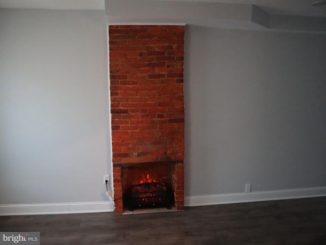 unfurnished living room featuring dark hardwood / wood-style floors and a brick fireplace