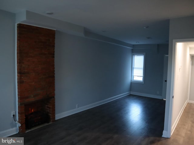 unfurnished living room featuring hardwood / wood-style flooring and a brick fireplace