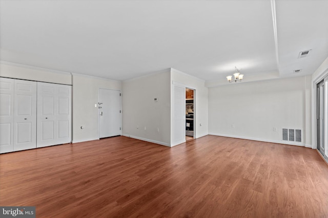 unfurnished living room with a notable chandelier and hardwood / wood-style floors