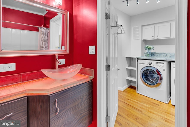 laundry area featuring cabinets, washer / dryer, light wood-type flooring, and sink