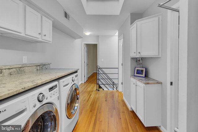 laundry area featuring cabinets, independent washer and dryer, and light hardwood / wood-style flooring