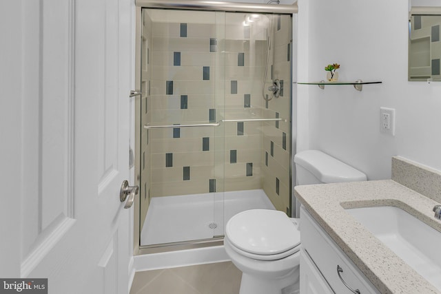 bathroom with tile patterned flooring, a shower with door, vanity, and toilet