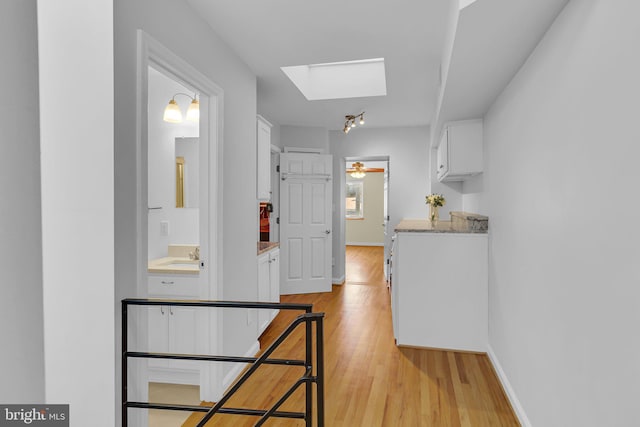 hall featuring a skylight and light hardwood / wood-style flooring