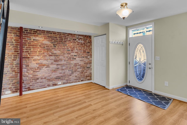 foyer entrance featuring light hardwood / wood-style floors and brick wall