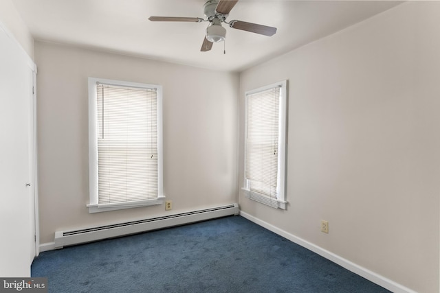 spare room with a baseboard heating unit, dark colored carpet, a wealth of natural light, and ceiling fan