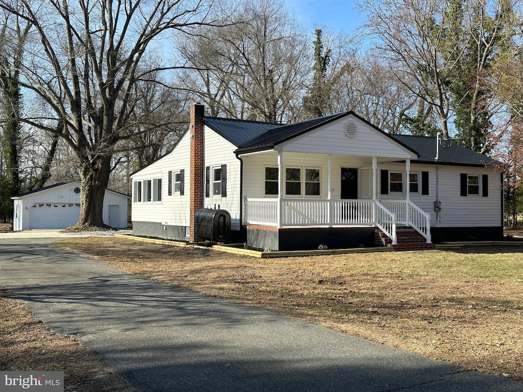 ranch-style house featuring an outbuilding, a garage, a front lawn, and covered porch