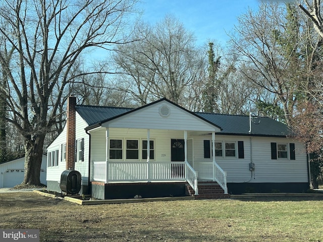 view of front of property with a front lawn, covered porch, an outdoor structure, and a garage