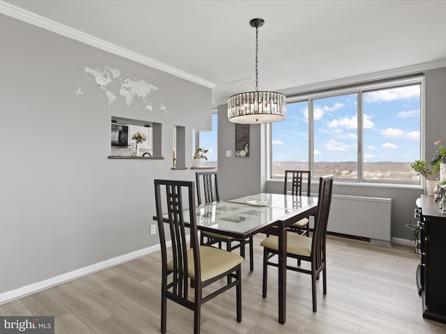 dining room with a notable chandelier, light wood-type flooring, and crown molding