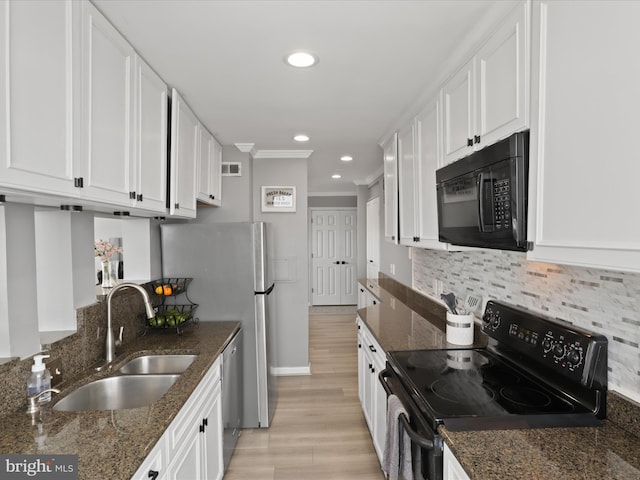 kitchen featuring sink, dark stone countertops, decorative backsplash, white cabinets, and black appliances