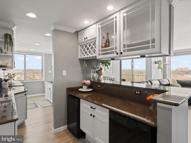 kitchen with ornamental molding, dark stone counters, light hardwood / wood-style flooring, dishwasher, and white cabinets