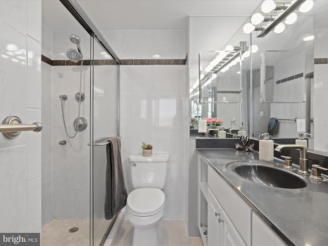 bathroom featuring tile patterned floors, an enclosed shower, toilet, vanity, and tile walls