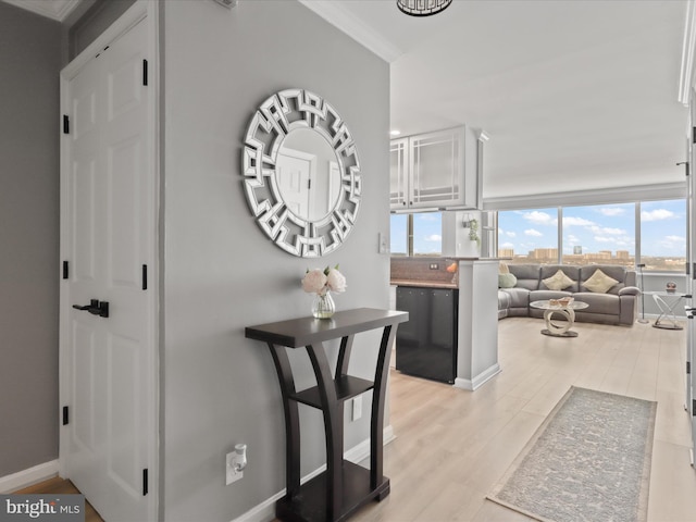 hall with light hardwood / wood-style floors and ornamental molding