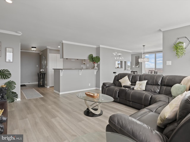 living room with ornamental molding, light hardwood / wood-style floors, and a notable chandelier