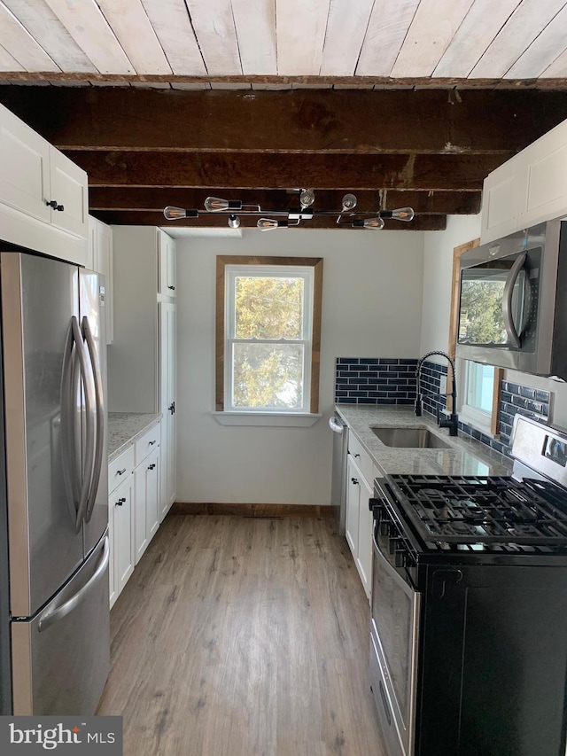 kitchen with white cabinets, stainless steel appliances, beamed ceiling, light hardwood / wood-style floors, and backsplash