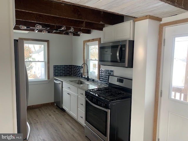 kitchen featuring white cabinets, light wood-type flooring, appliances with stainless steel finishes, and sink