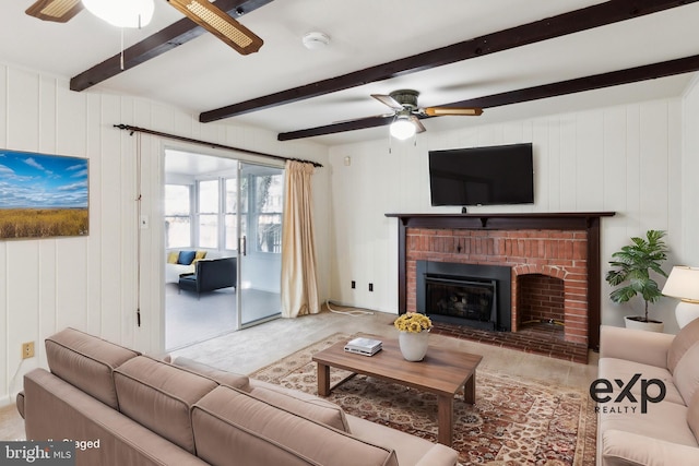 living area with a ceiling fan, a fireplace, and beamed ceiling