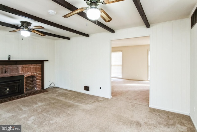 unfurnished living room with carpet, beamed ceiling, a fireplace, and visible vents