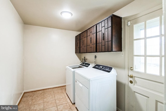 laundry area featuring washing machine and dryer, cabinet space, baseboards, and light tile patterned flooring