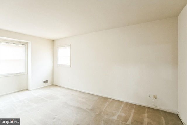 empty room with light colored carpet, visible vents, and baseboards