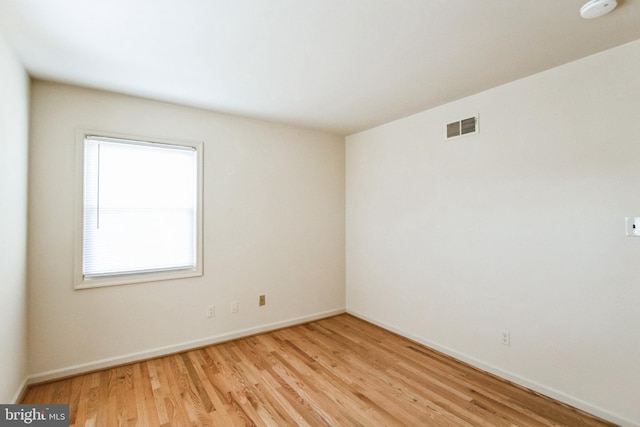 empty room with light wood finished floors, baseboards, and visible vents