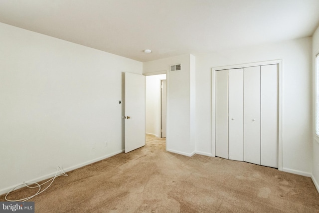 unfurnished bedroom with a closet, carpet flooring, visible vents, and baseboards