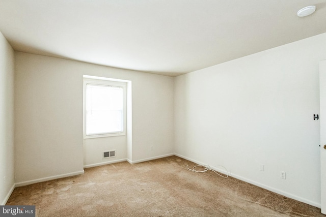 spare room with light colored carpet, visible vents, and baseboards