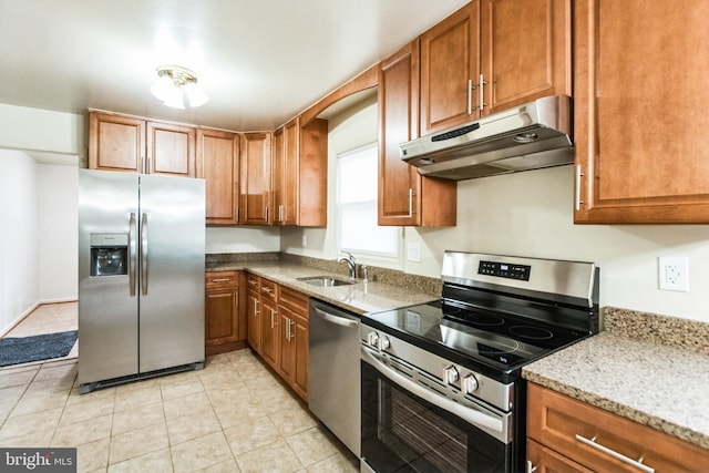 kitchen with under cabinet range hood, appliances with stainless steel finishes, brown cabinets, and a sink