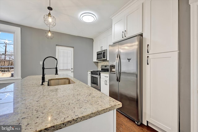 kitchen with pendant lighting, sink, stainless steel appliances, and light stone countertops