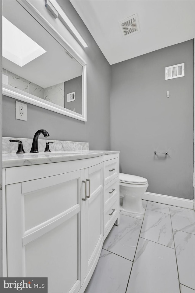 bathroom featuring a skylight, vanity, and toilet