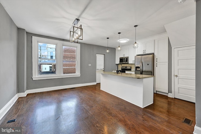 kitchen featuring white cabinetry, hanging light fixtures, a kitchen island with sink, stainless steel appliances, and light stone countertops