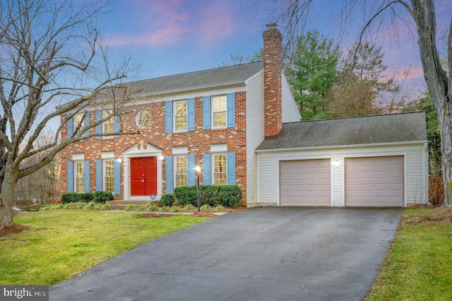 colonial house featuring a lawn and a garage