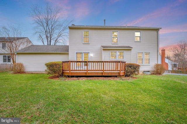 back house at dusk featuring a yard and a wooden deck