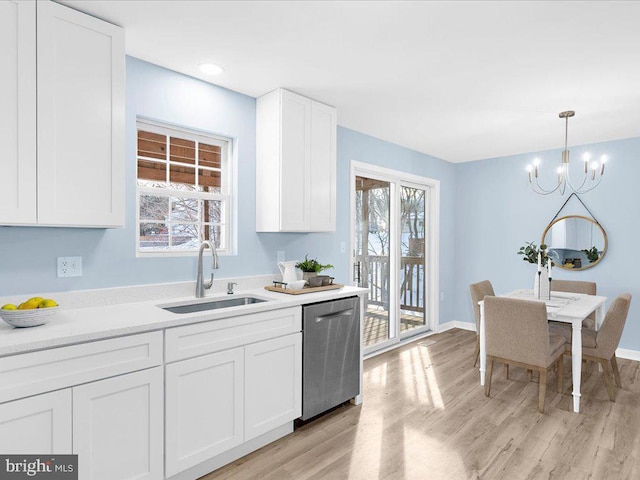 kitchen featuring a sink, white cabinetry, light countertops, dishwasher, and decorative light fixtures