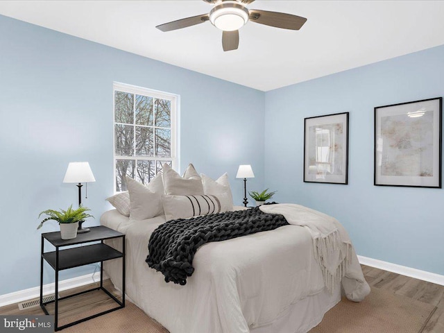 bedroom featuring visible vents, wood finished floors, a ceiling fan, and baseboards