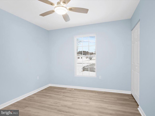 unfurnished room with light wood-type flooring, a ceiling fan, and baseboards