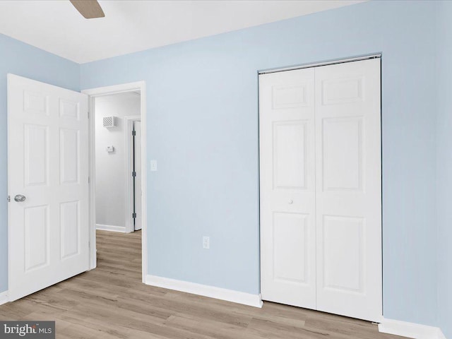 unfurnished bedroom featuring light wood-type flooring, a closet, and baseboards