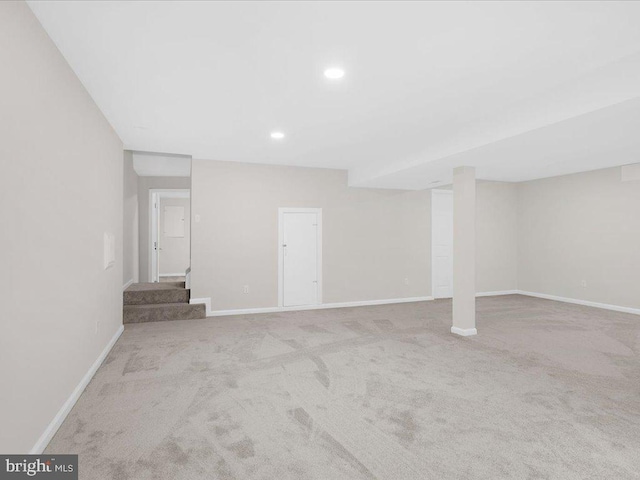 finished basement with baseboards, stairway, recessed lighting, and light colored carpet