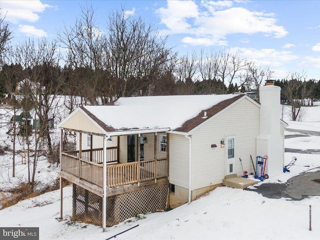 snow covered back of property featuring a chimney