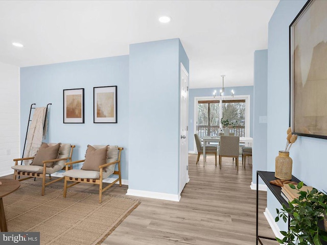 living area featuring recessed lighting, light wood-style flooring, baseboards, and an inviting chandelier