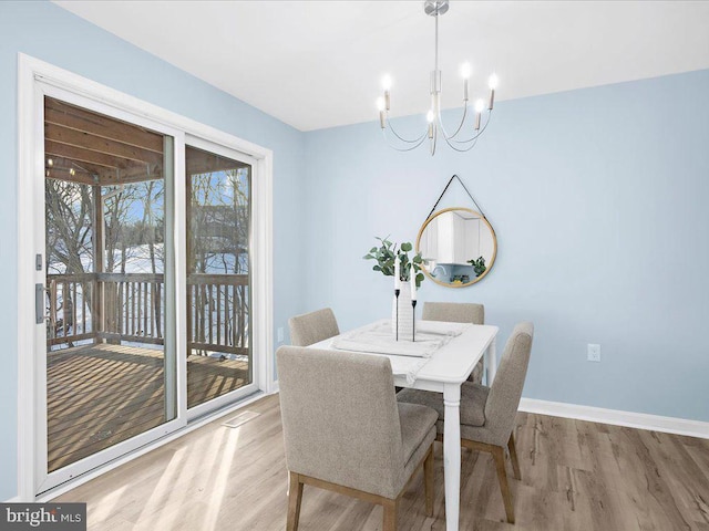 dining area featuring a notable chandelier, baseboards, and light wood-style floors