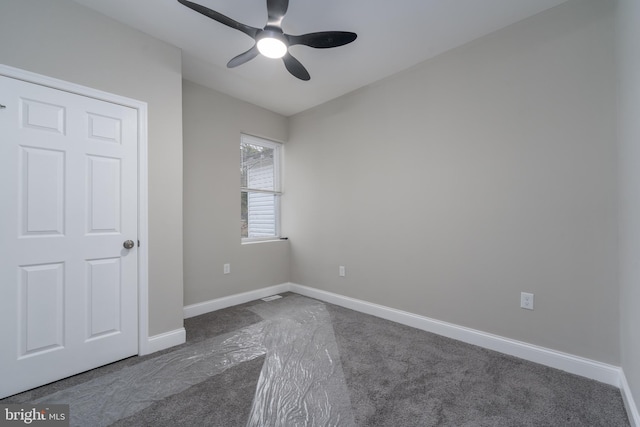 unfurnished bedroom with ceiling fan and dark carpet