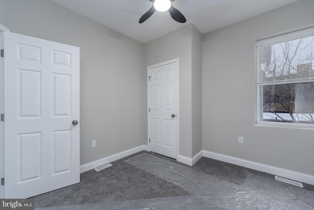 unfurnished bedroom with ceiling fan and dark carpet