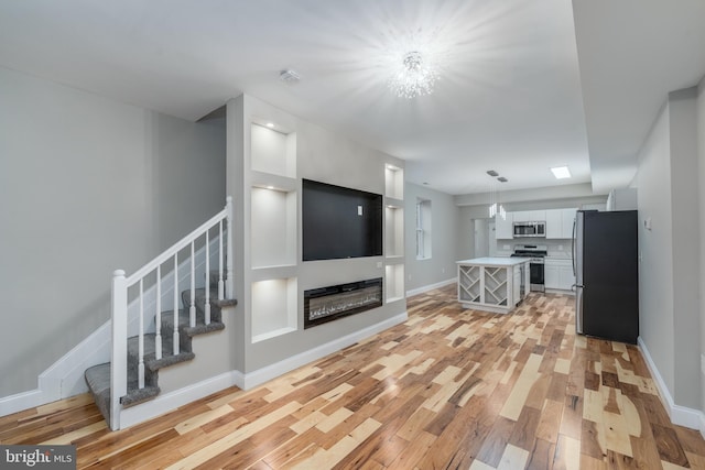 unfurnished living room with light hardwood / wood-style flooring and a chandelier