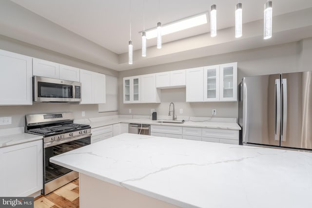 kitchen with white cabinets, appliances with stainless steel finishes, sink, and pendant lighting