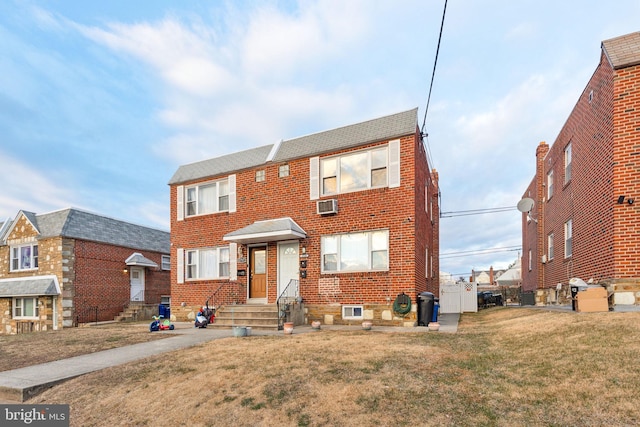 view of front of home featuring an AC wall unit and a front lawn