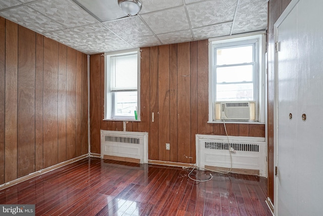 spare room with dark hardwood / wood-style floors, radiator heating unit, and wooden walls