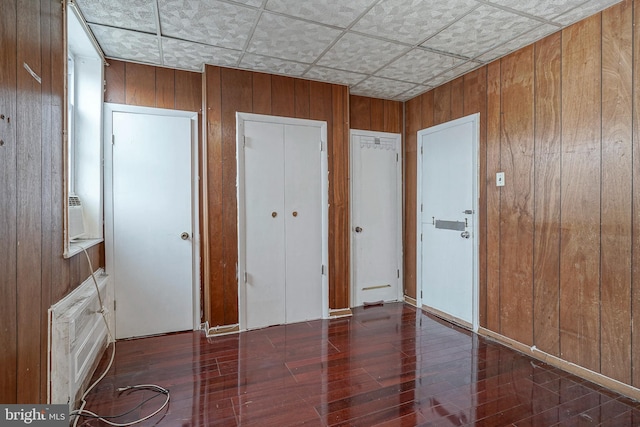 unfurnished bedroom featuring dark hardwood / wood-style flooring and wood walls