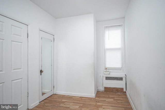 hall featuring radiator heating unit and light hardwood / wood-style floors